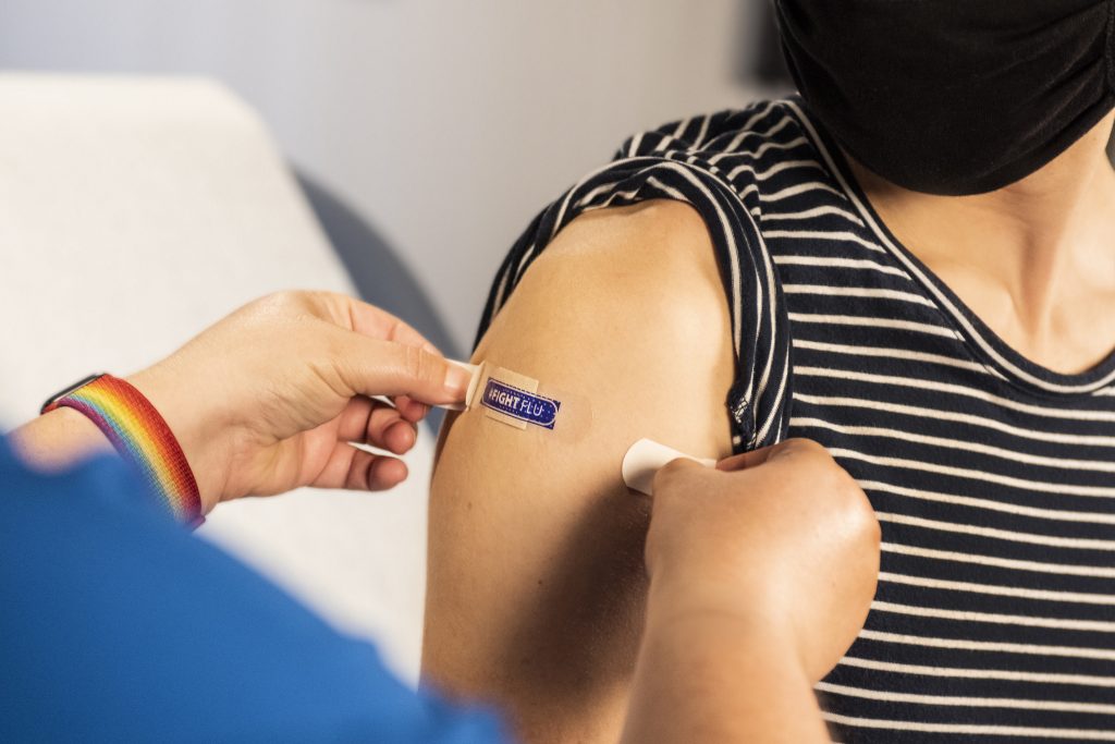 In this 2020 photograph, captured inside a clinical setting, a health care provider places a bandage on the injection site of a patient, who just received an influenza vaccine. The best way to prevent seasonal flu, is to get vaccinated every year. Centers for Disease Control and Prevention (CDC) recommends everyone 6-months of age and older, get a flu vaccine every season.