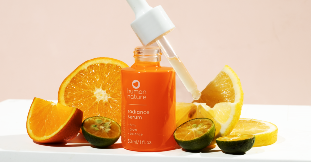 Human Nature Vitamin C + Hya Calamansi Radiance Serum with dropper, surrounded by orange, lemon, and calamansi slices